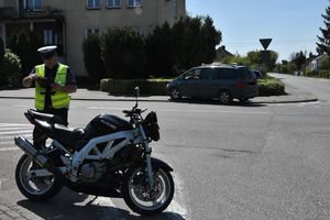 policjant na miejscu zdarzenia stoi przy motocyklu.