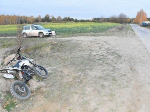 miejsce zdarzenia. Poza drogą leży motocykl. W tle radiowóz.