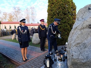 policjanci  składają znicz pod pomnikiem.