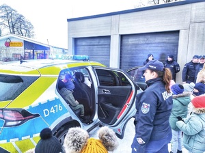 dzieci oglądają radiowóz pod opieką policjantów i opiekunów