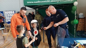 policjanci pomagają przymierzyć dzieciom umundurowanie.