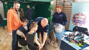 policjanci pomagają przymierzyć dzieciom elementy umundurowania