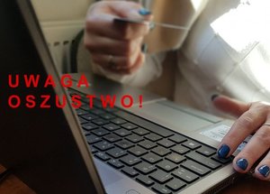 dłonie na klawiaturze laptopa i napis uwaga oszustwo