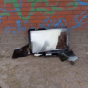 uszkodzony telewizor oparty o ścianę budynku