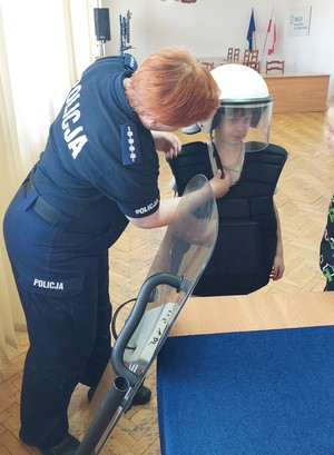 policjantka pomaga założyć dziecku elementy umundurowania