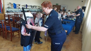 policjantka pomaga przymierzyć dzieciom elementy umundurowania