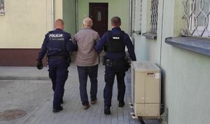 policjanci prowadzą zatrzymanego mężczyznę