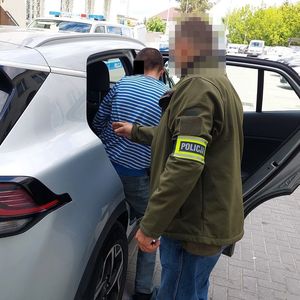 policjant wprowadza mężczyznę do radiowozu