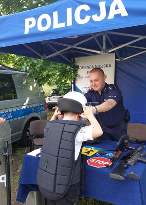 policjant pomaga dziecku założyć elementy wyposażenia