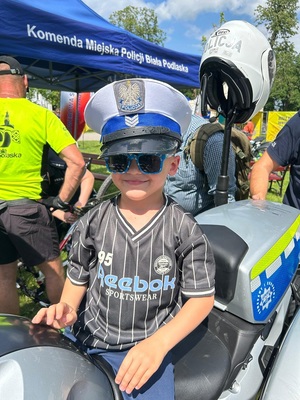dziecko w policyjnej czapce siedzi na motocyklu