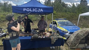 Kobieta z prezentowana przez policje bronią stojący przy stoisku policyjnym