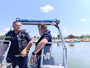 policjanci stoją na łodzi. W tle kąpielisko