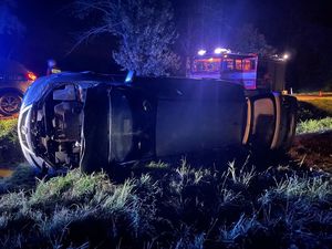 samochód leży na boku. Za nim auto służb