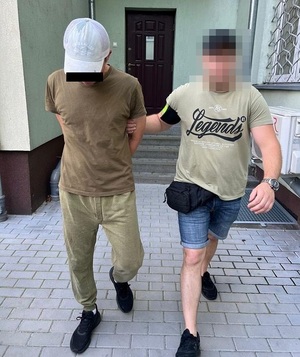 policjant prowadzi zatrzymanego mężczyznę