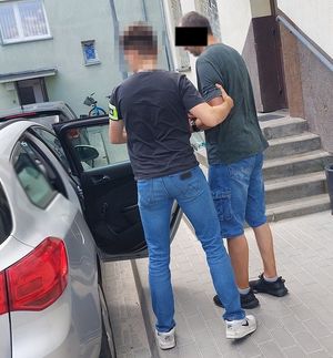 policjant wprowadza zatrzymanego