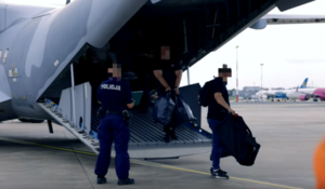 policjant zabezpiecza konwój zatrzymanych osób, które wysiadają z samolotu&quot;