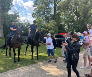 osoby stojące nieopodal patrolu konnego robią zdjęcia policjantom