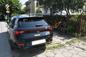 samochód i rower oparty o ogrodzenie posesji