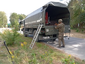 pojazd służbowy i saper wkładający niewybuch do samochodu