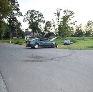 miejsce zdarzenie. Uszkodzone samochody. Policjant wykonuje czynności przy jednym z nich