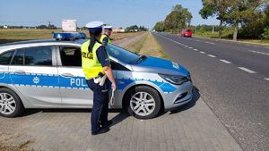 policjanci ruchu drogowego w trakcie służby stoją przy radiowozie