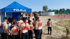 stoisko policyjne. Grupa dzieci stoi przy stoisku