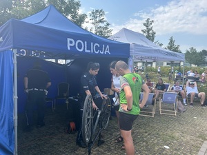 policjantka przy stoisku rozmawia z osobami, które chcą oznakować rower