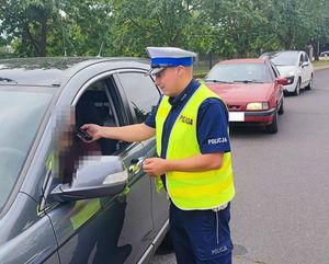 policjant ruchu drogowego sprawdzający trzeźwość kierowcy samochodu osobowego