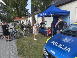 policjanci przy stoisku i osoby czekające na oznakowanie roweru