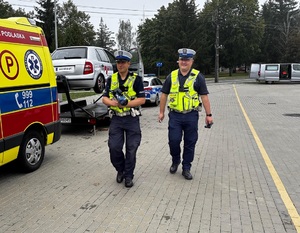 dwaj policjanci idą obok karetki