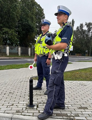 policjanci rd podczas służby stoją na chodniku kontrolując zachowania kierowców