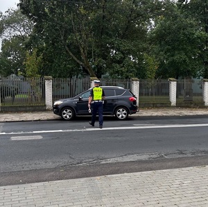 policjant podchodzi do samochodu osobowego
