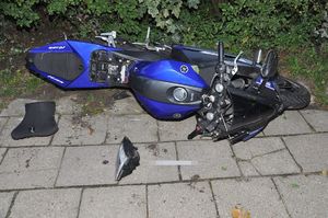 motocykl leży częściowo na chodniku