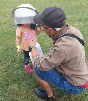 dziecko przymierza hełm policyjny. Obok rodzic