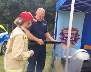 policjant pokazuje dziewczynce broń