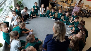 policjantka siedzi w kółku z uczniami