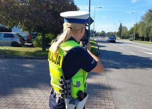 policjantka kontroluje prędkość nadjeżdżających samochodów miernikiem prędkości