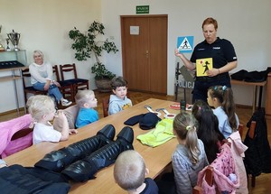 policjantka podczas spotkania z dziećmi prezentuje znaki drogowe