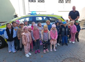 dzieci oraz policjant stoją przy radiowozie