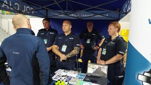 policjanci przy stoisku rozmawiają z człowiekiem