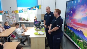 policjanci rozmawiają z dziećmi siedzącymi w ławce