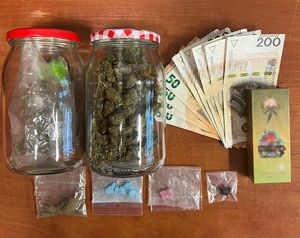 zabezpieczone narkotyki znajdujące się w szklanych słoikach i woreczkach foliowych . Obok leżą pieniądze
