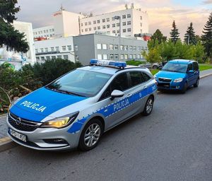 radiowóz i stojący  za nim eskortowany samochód