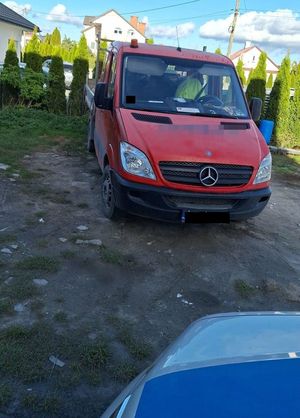 samochód stoi na posesji, obok fragment radiowozu