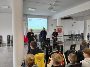 policjanci stoją przed stołem prezydialnym rozmawiają z uczestnikami debaty