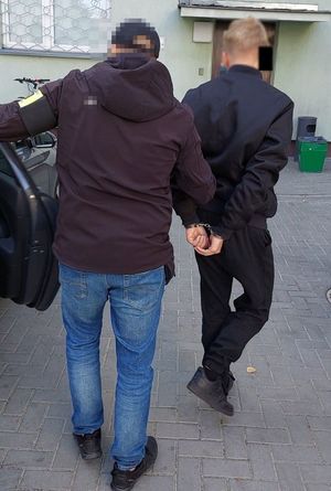 policjant wprowadza zatrzymanego