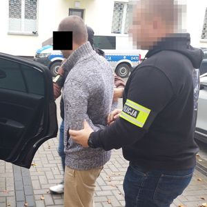 policjanci wprowadzają zatrzymanego do radiowozu