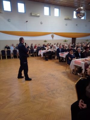 umundurowany policjant prowadzi rozmowę z seniorami