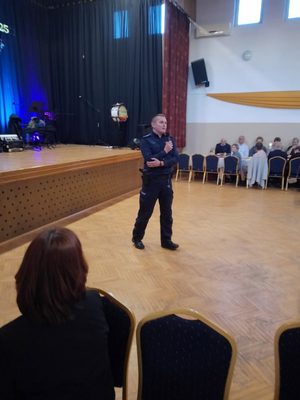 umundurowany policjant prowadzi rozmowę z seniorami