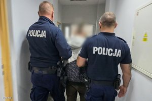 umundurowani policjanci prowadzący zatrzymanego